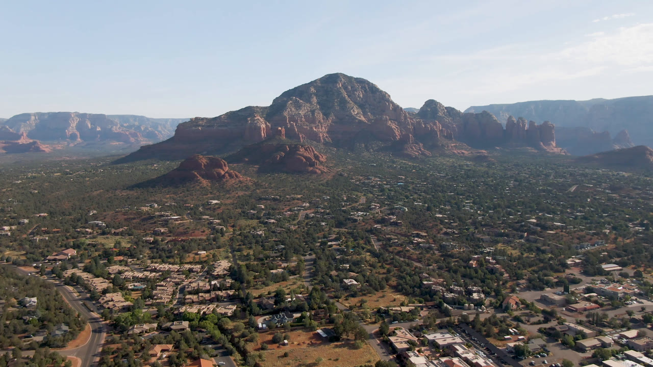 Aerial view of Sedona roads, buildings, and red rock mountains in warm daylight