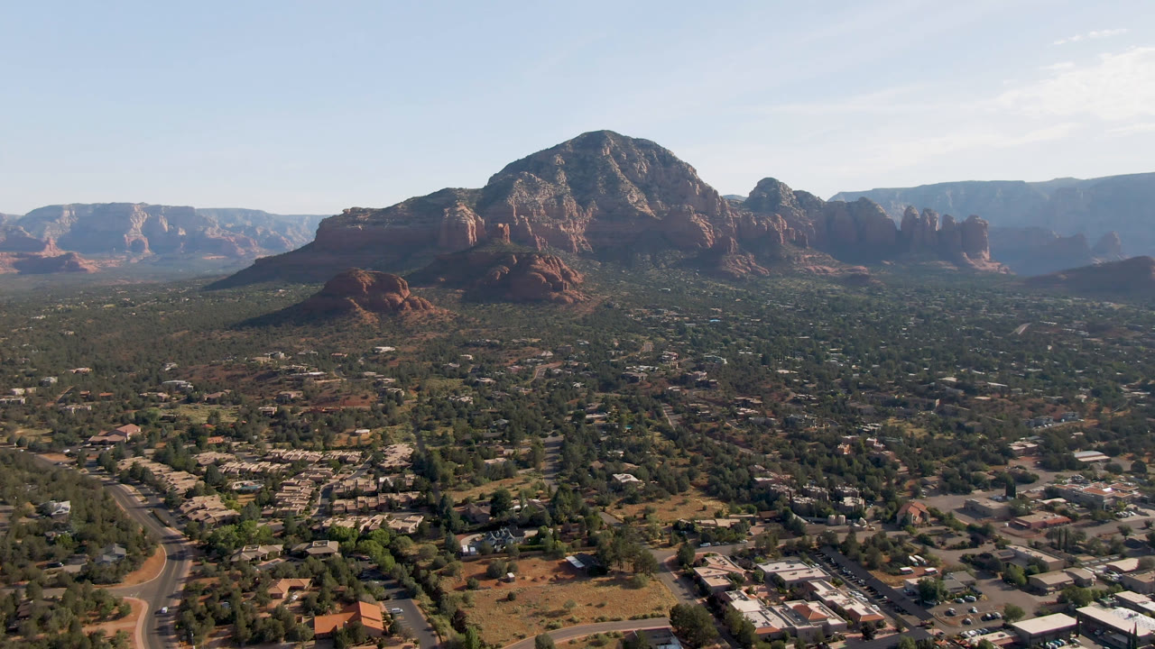 Desert town foreground with red rock mountains under a bright sky.