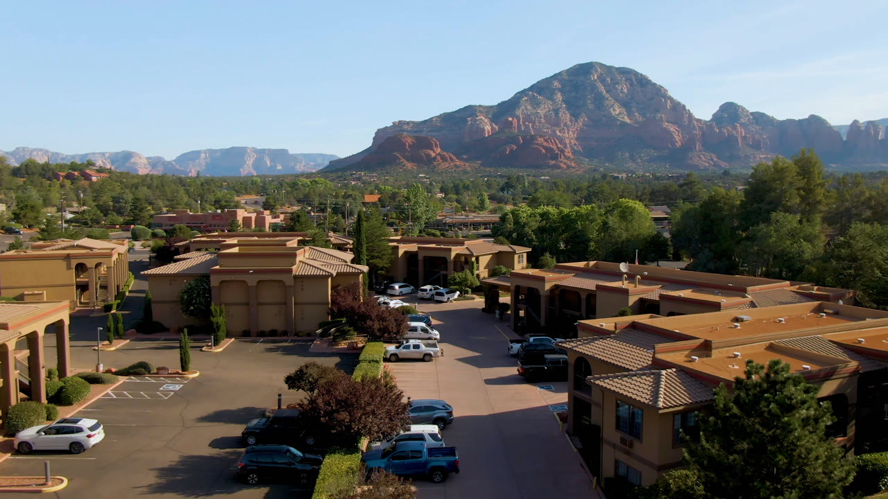 Wide aerial view of a town parking area with mountains on the horizon.