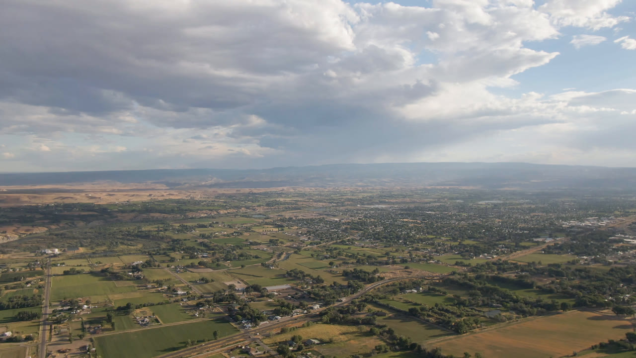 Aerial frame over Palisades, Colorado, showing a patchwork of fields, scattered settlement, diagonal roads, distant terrain, and no visible people.