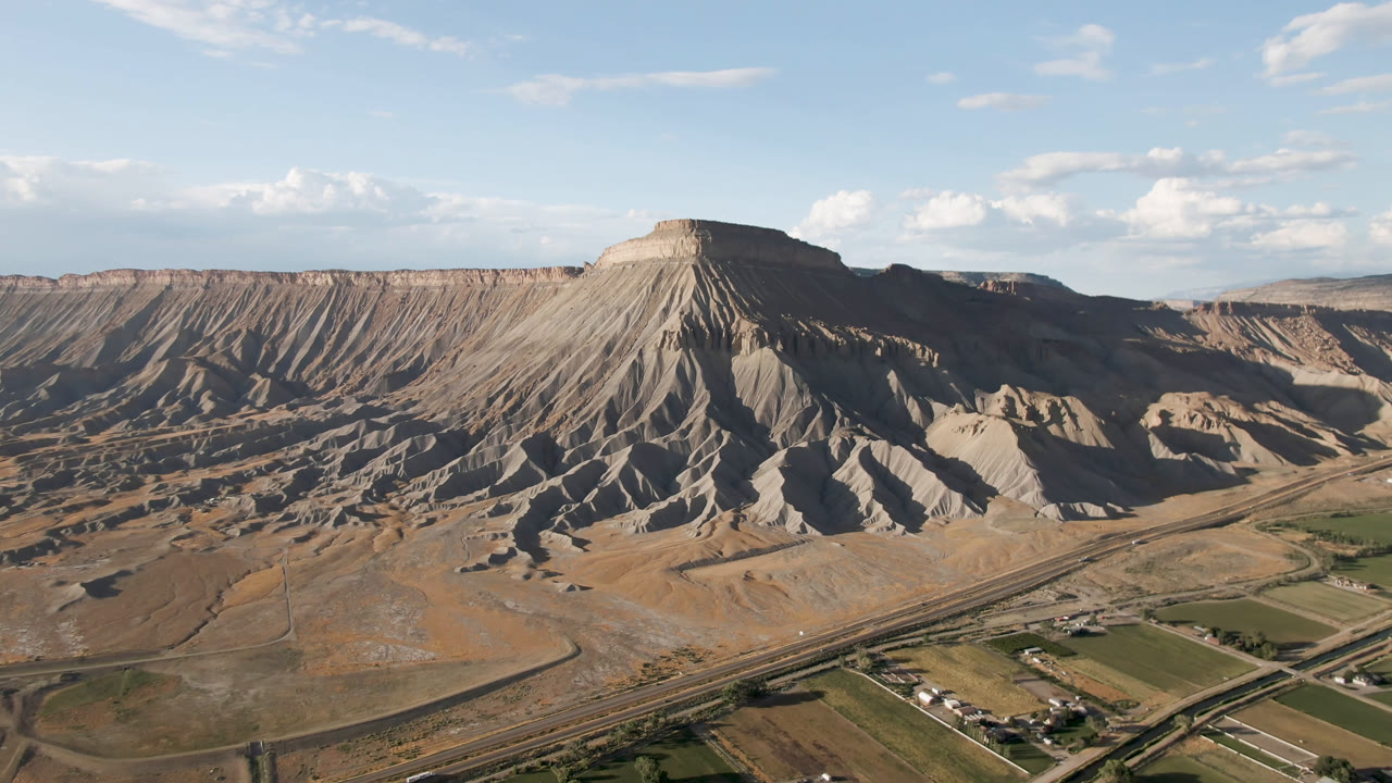 Aerial view of a flat-topped eroded mountain above roads and farm fields.