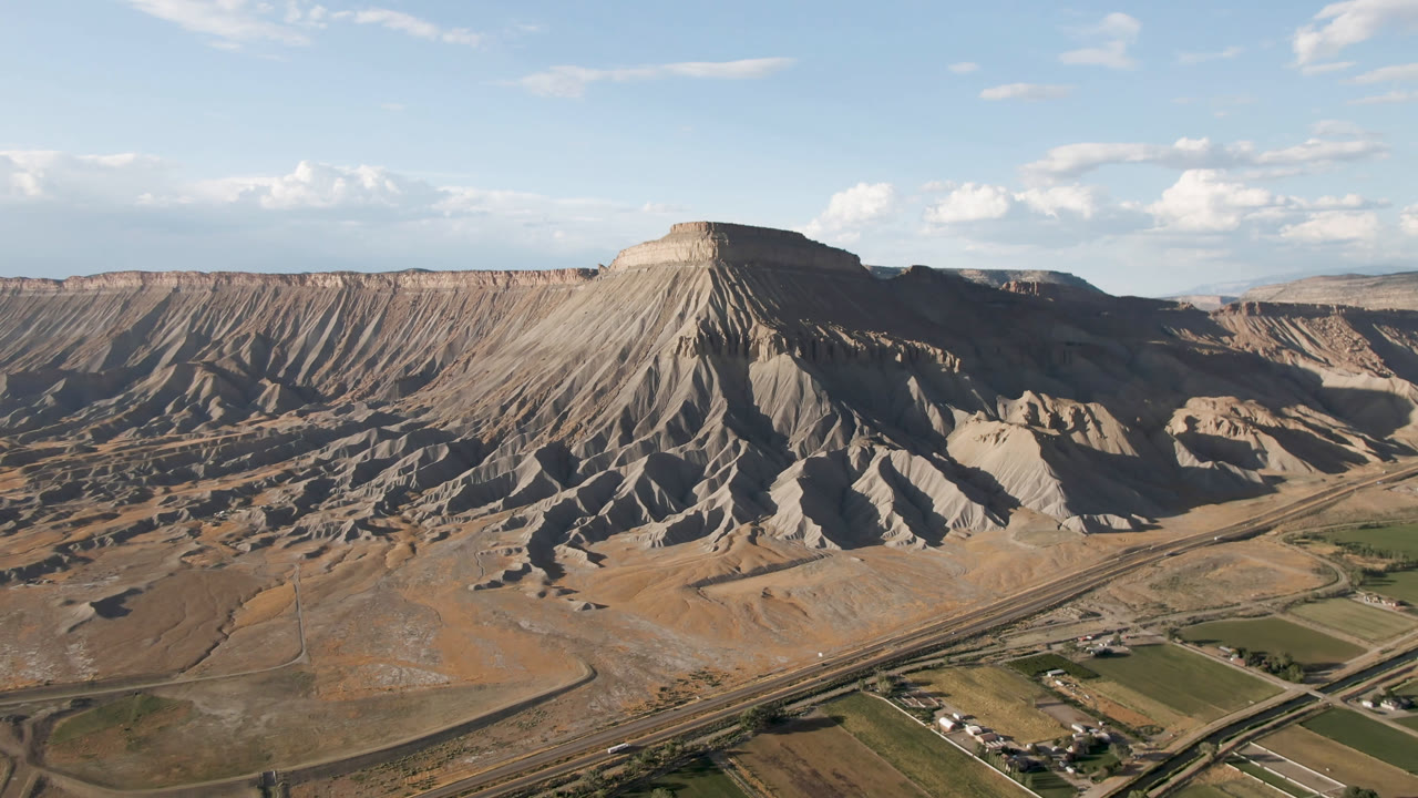 Aerial view of a flat-topped mesa above a dry valley with roads and fields.