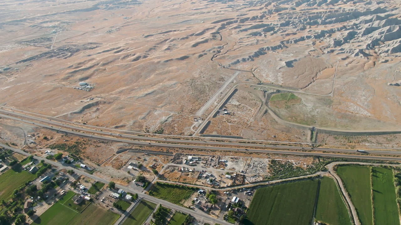 High aerial view of roads, desert terrain, and green fields.