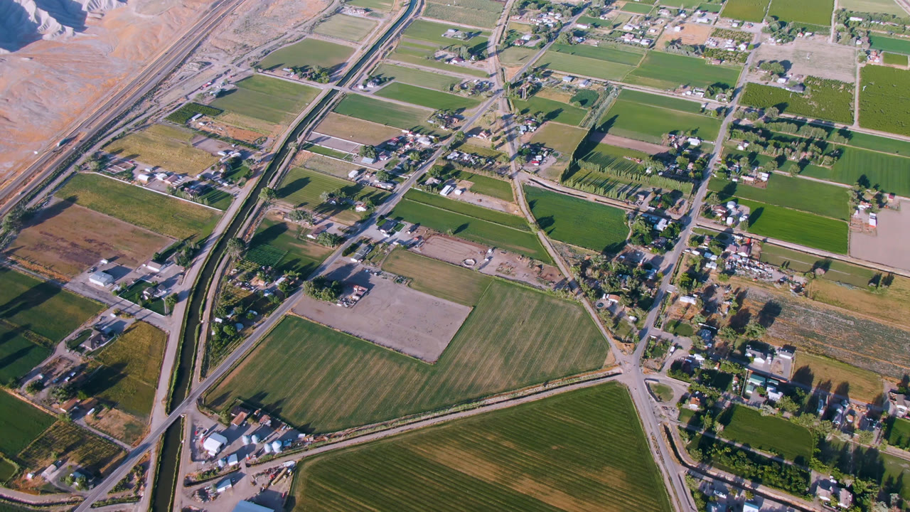 Second aerial frame of Palisades, Colorado with rectangular fields, road junctions, clusters of homes, tree rows, and no visible people.