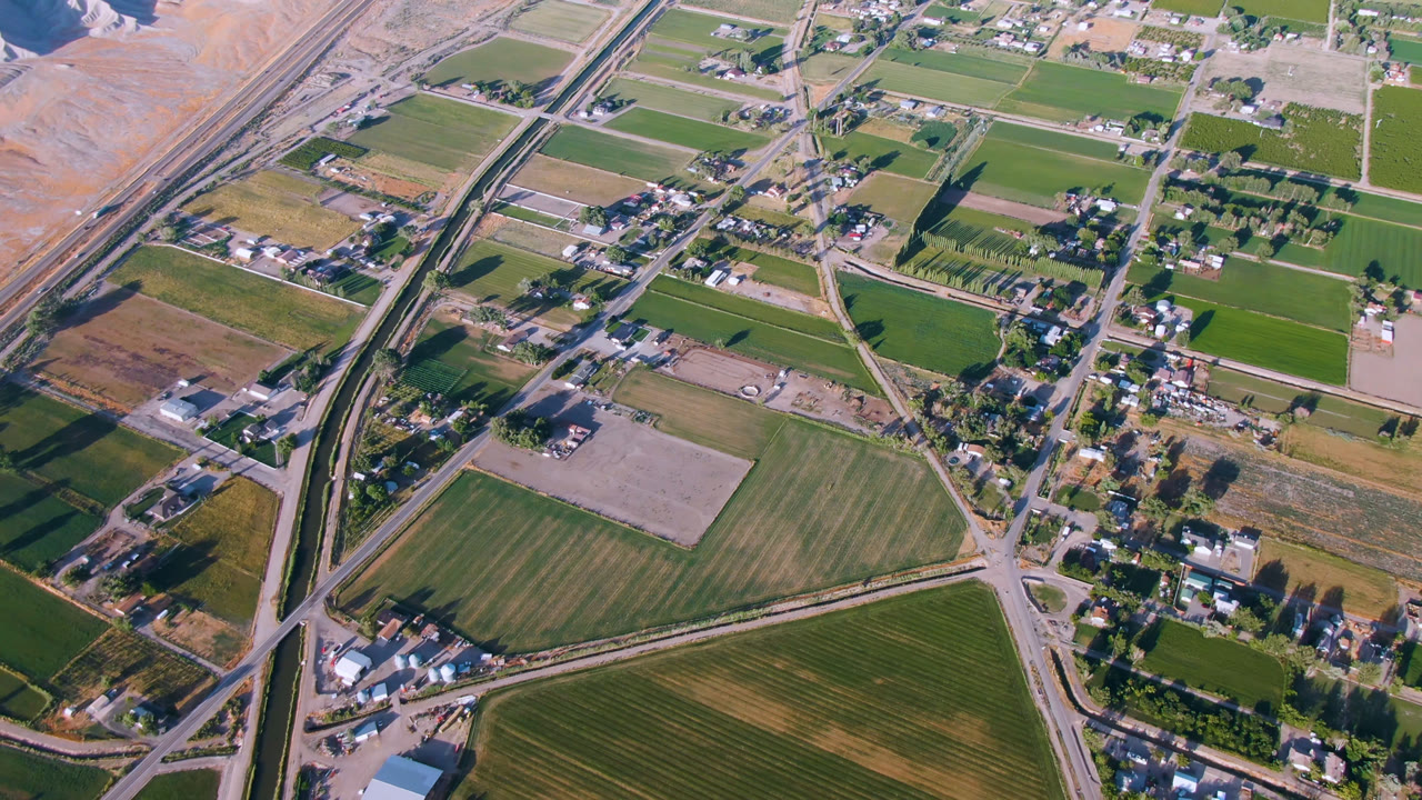 Oblique aerial over green fields, homes, roads, and dry slope