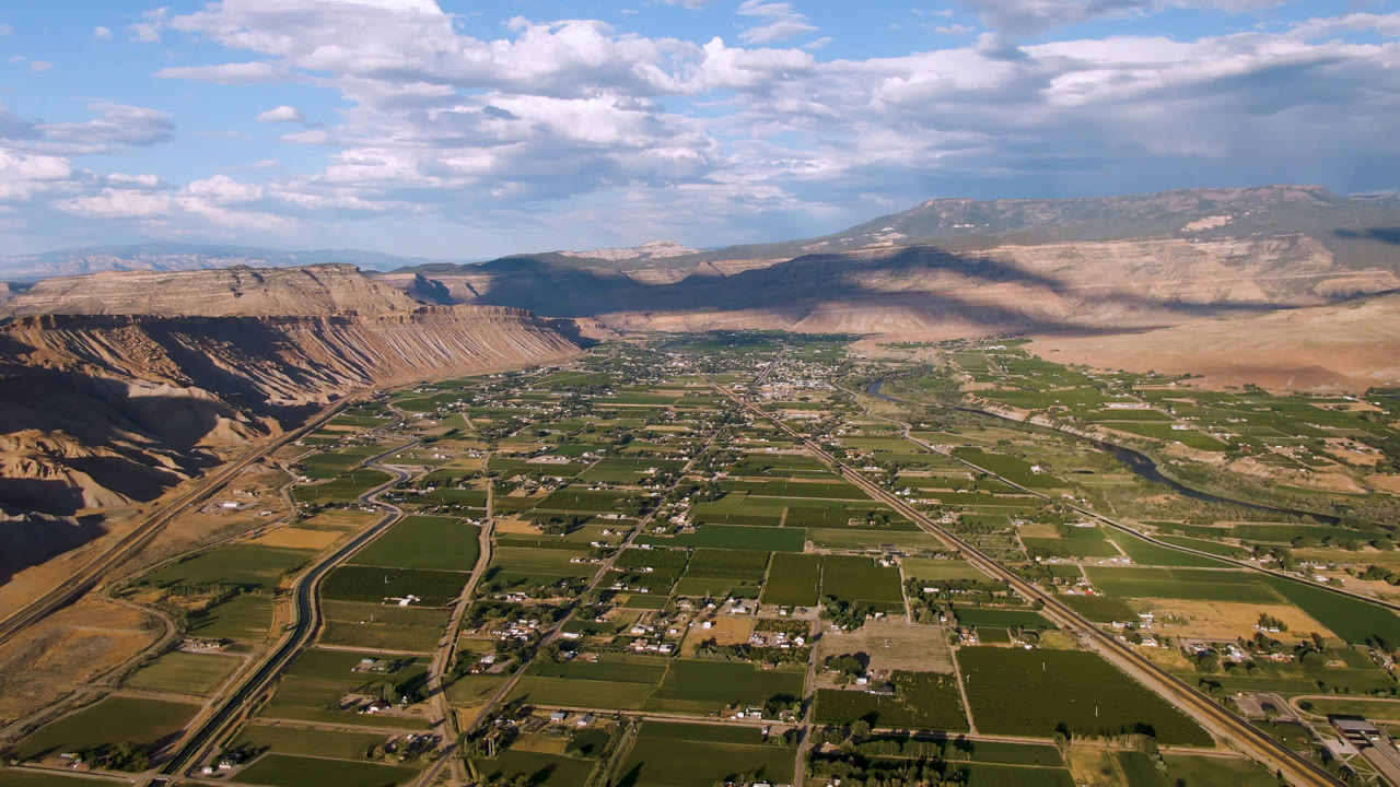Aerial valley view with farmland, small settlement, road grid, and mountain ridges.