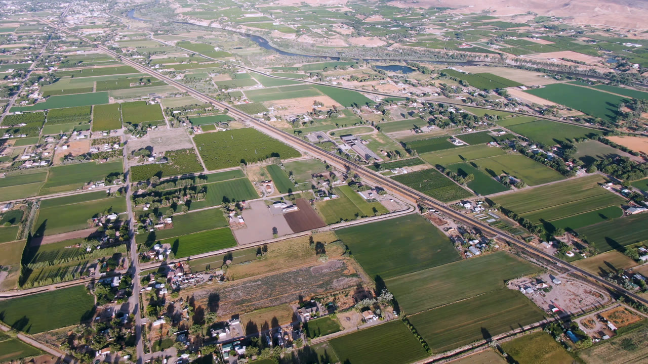Aerial view of farm fields, roads, scattered buildings, and distant dry hills.