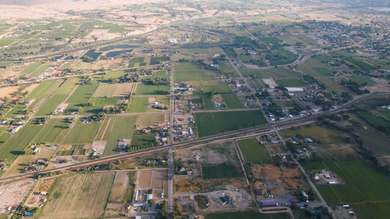 Aerial view of fields, roads, scattered buildings, and distant hills