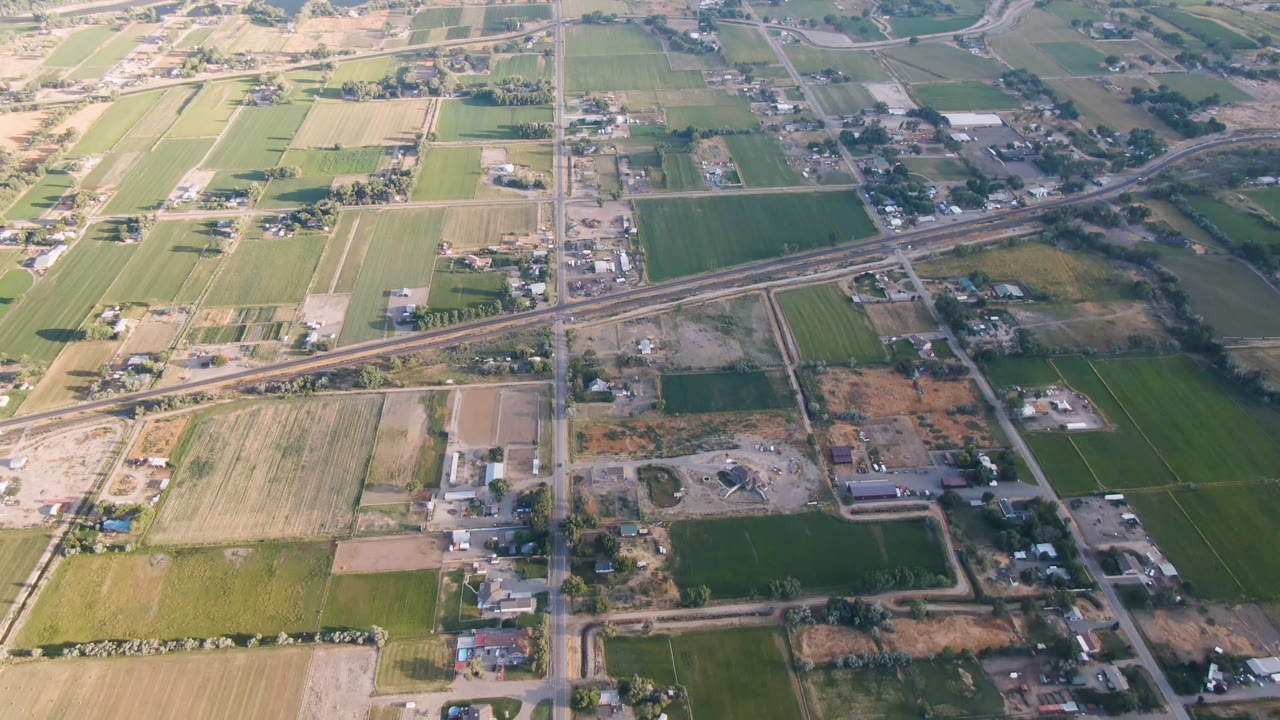 Second aerial frame over Palisades, Colorado with the rail corridor cutting across midframe, rectangular fields, small structures, and no visible people.
