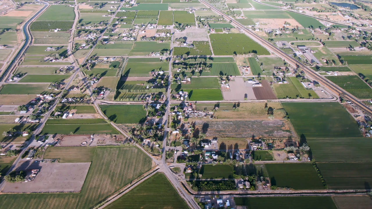Aerial view of rural blocks, fields, roads, and a water channel.