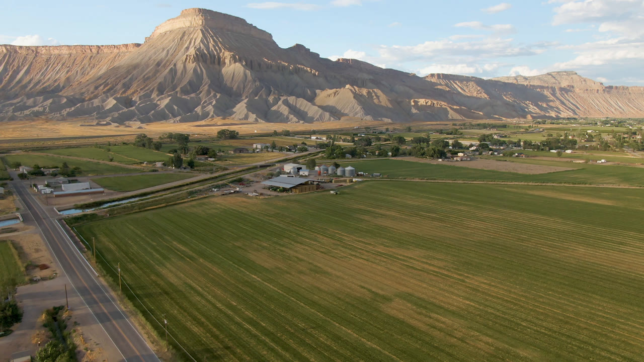 Aerial view of farm fields, road, buildings, and a mountain ridge.