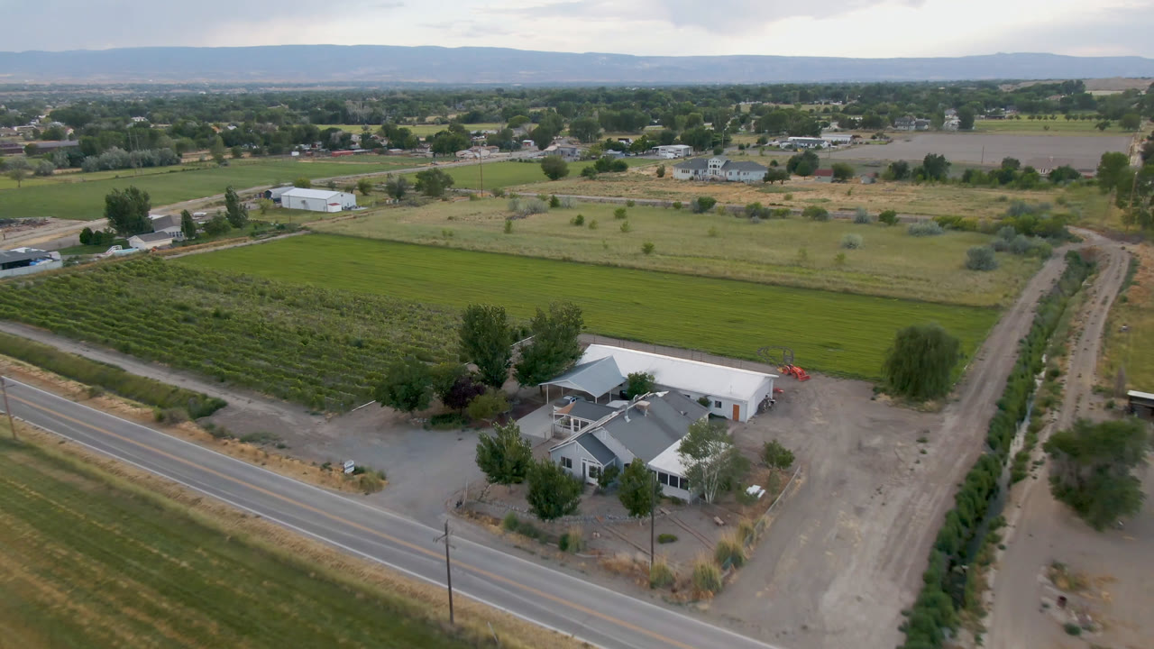 Aerial view of a farmhouse, road, fields, and distant hills.