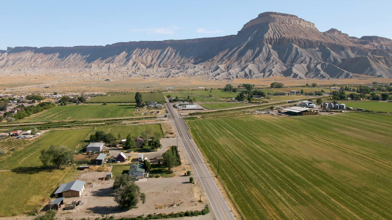 Aerial view of fields, road, farm buildings, and desert mountains
