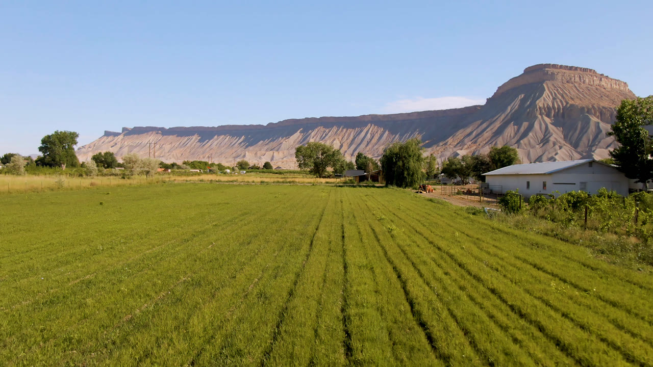 At 0:02, the white building sits near the right edge while the green field rows and broad Palisades mountain backdrop dominate the frame, with no visible people.