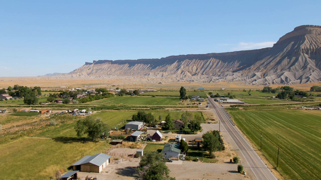 Rural settlement and farm plots below a large mesa in clear daylight.