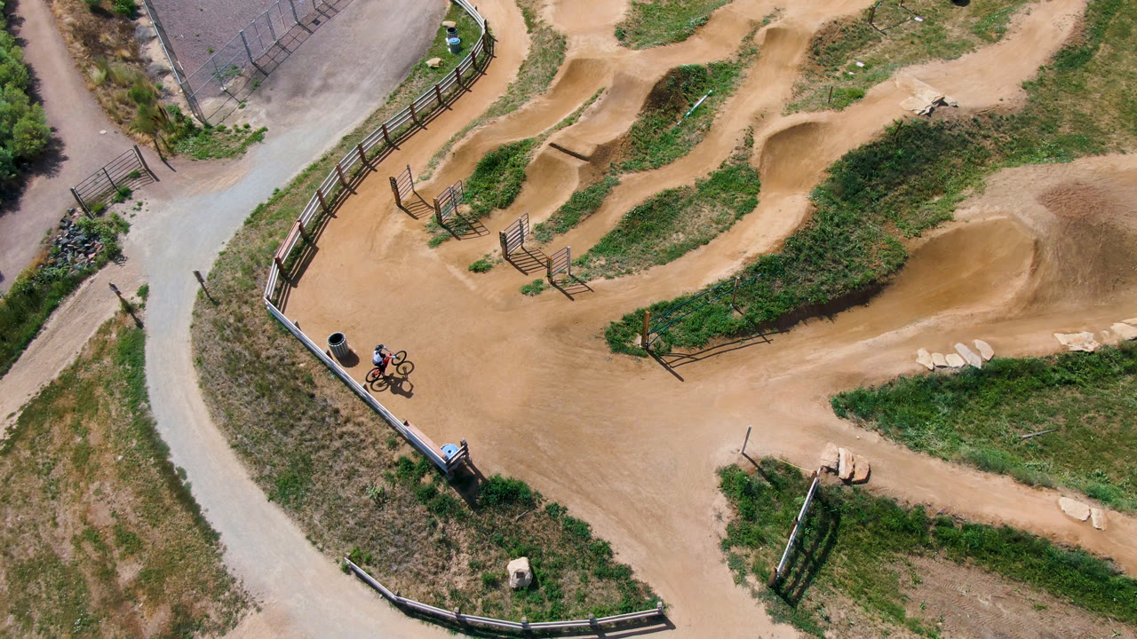 Overhead BMX park with a distant rider beside the course entrance.