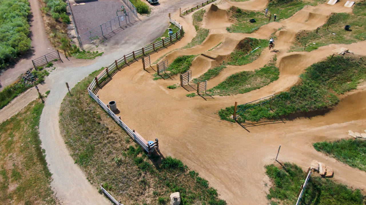 Aerial view of a dirt bike park with looping tan tracks and grassy areas.