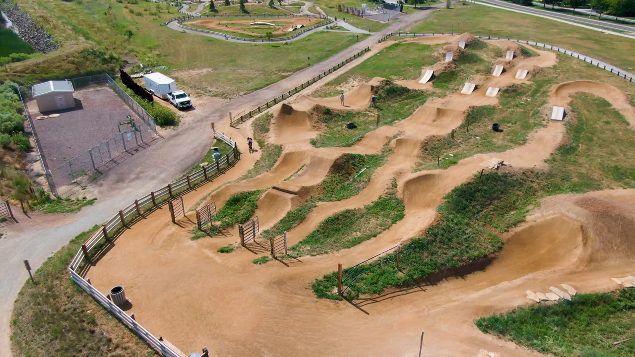 High-angle view of the dirt course with fence, paved road, and grassy surroundings.