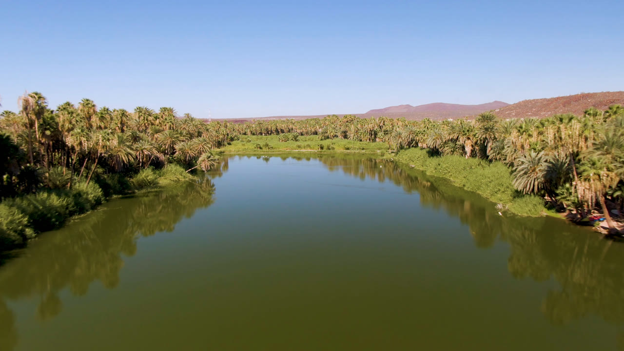 Second frame shows the San Ignacio river bend from above, with still green water, dense palms on the banks, dry hills on the horizon, and no visible people.