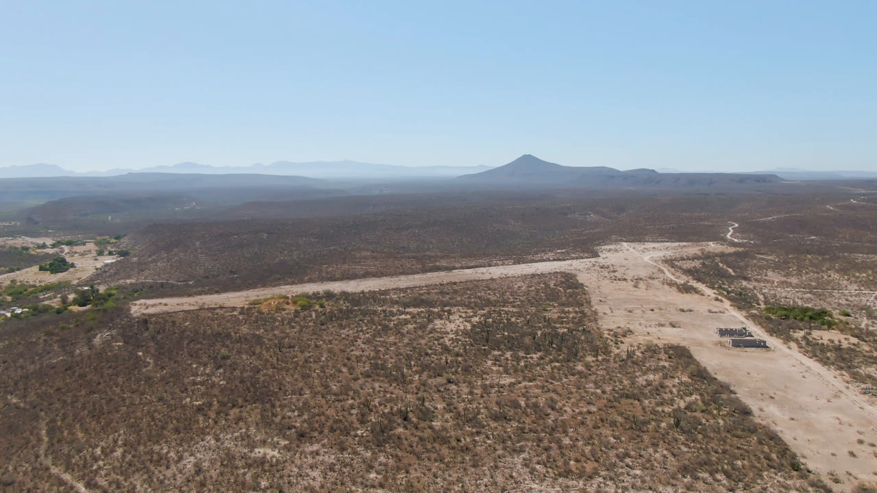 Desert road and scrubland viewed from above under a clear blue sky.