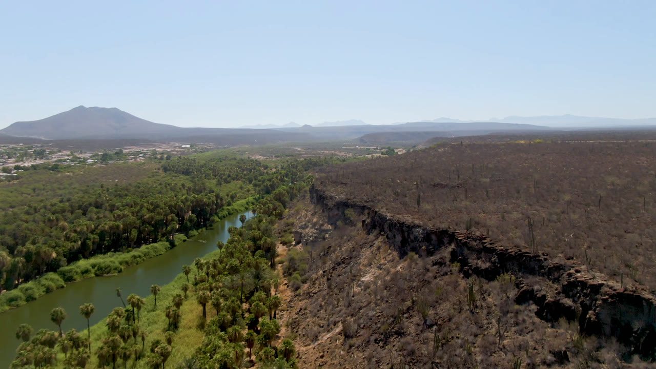 River bends through trees below a broad rocky desert surface