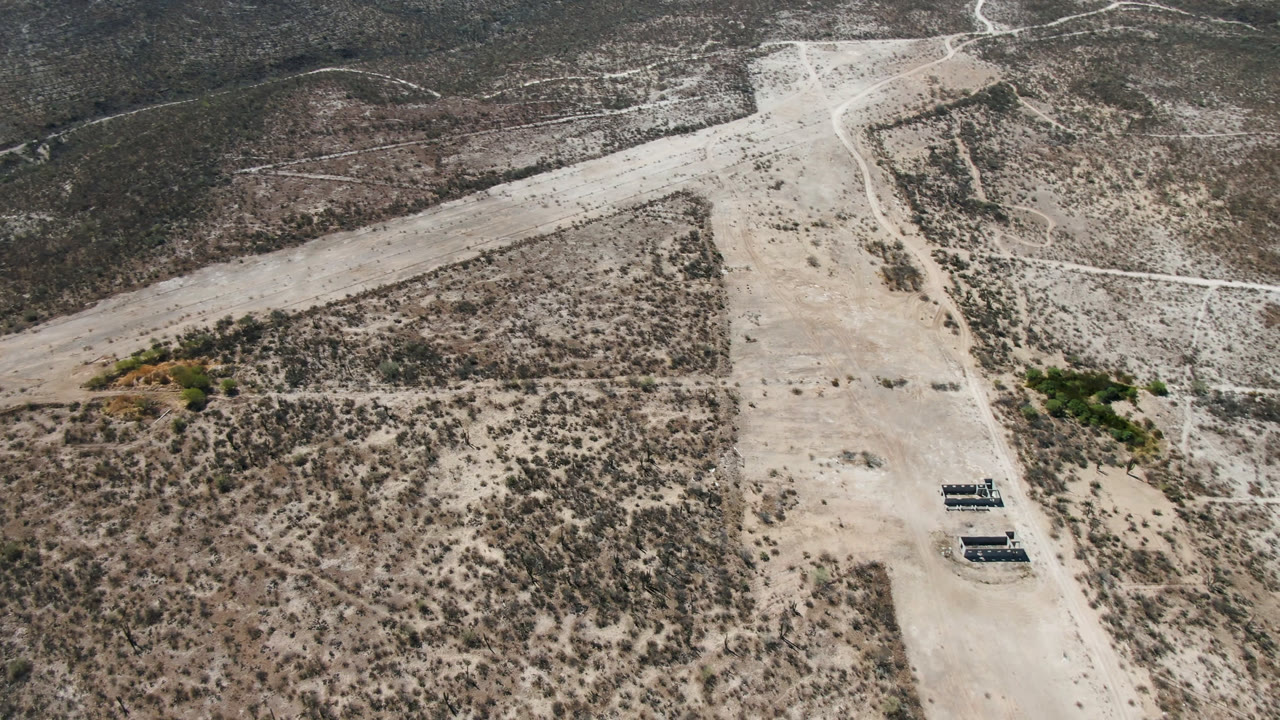 High aerial over desert road with small objects near the roadside