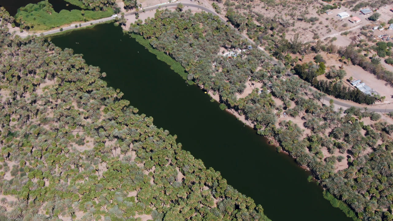 Overhead river bordered by dense trees and dry terrain.