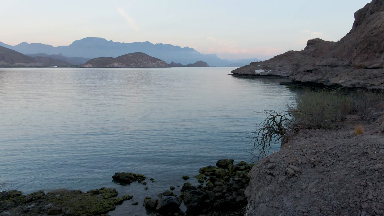 Rocky bay shoreline with calm water and distant mountains