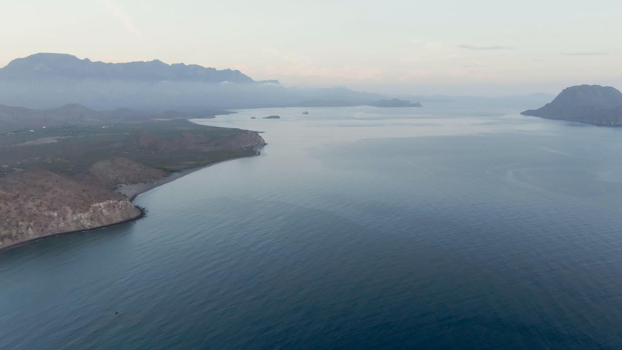 Second frame from Danzante Bay Loreto shows the headland shifted slightly across the lower left, broad bay water, small distant islands, hazy mountains, and no visible people.