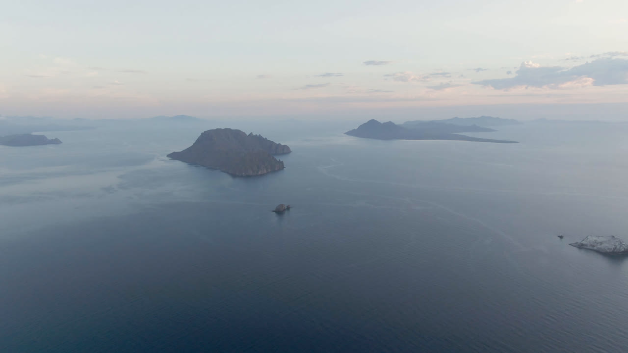At one second, the Danzante Bay aerial view holds on the island and horizon while a small boat sits near center-right and a larger vessel remains low in the frame, with no visible people.