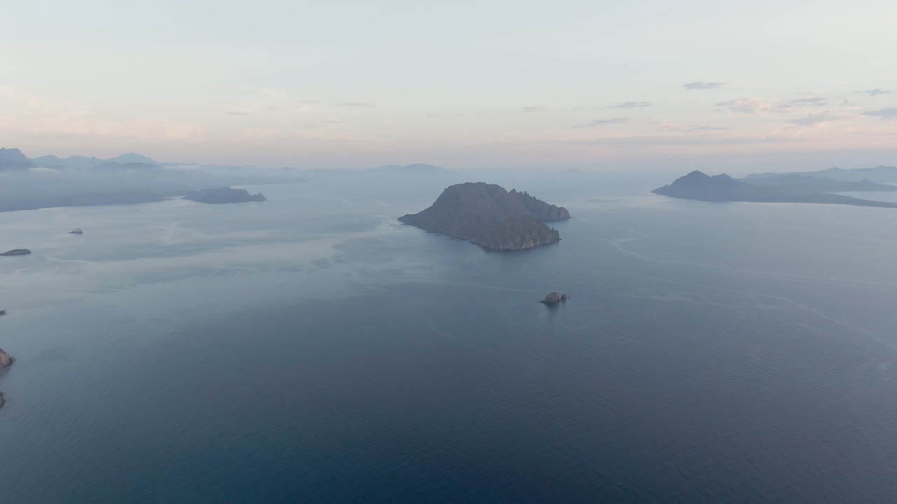 Open ocean and island silhouettes under a pale sky, with a small boat near the lower frame.