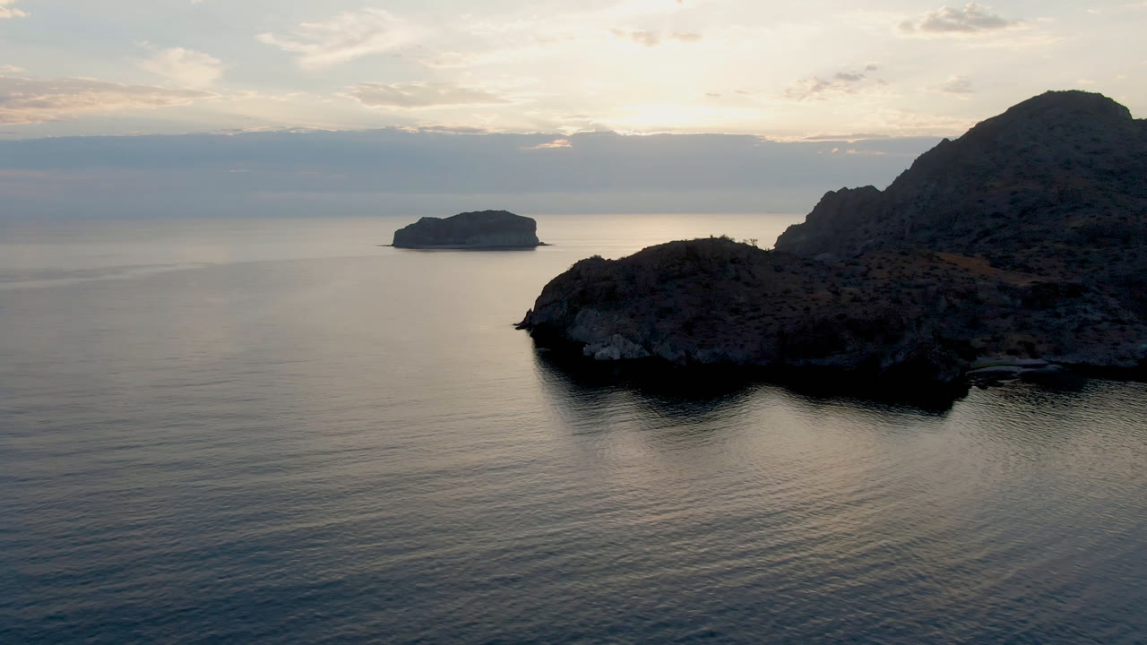 Rocky bay edge with calm sea and muted cloud light.