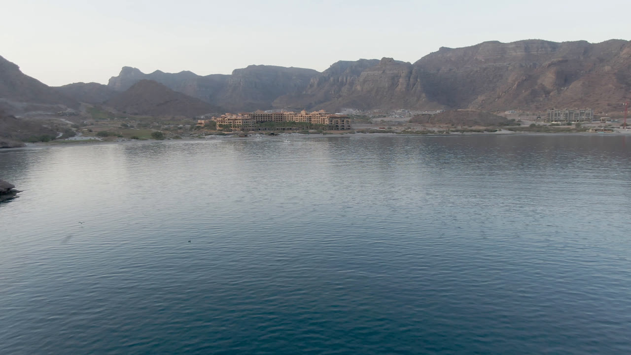 Wide bay water with mountains and shoreline buildings in the distance.