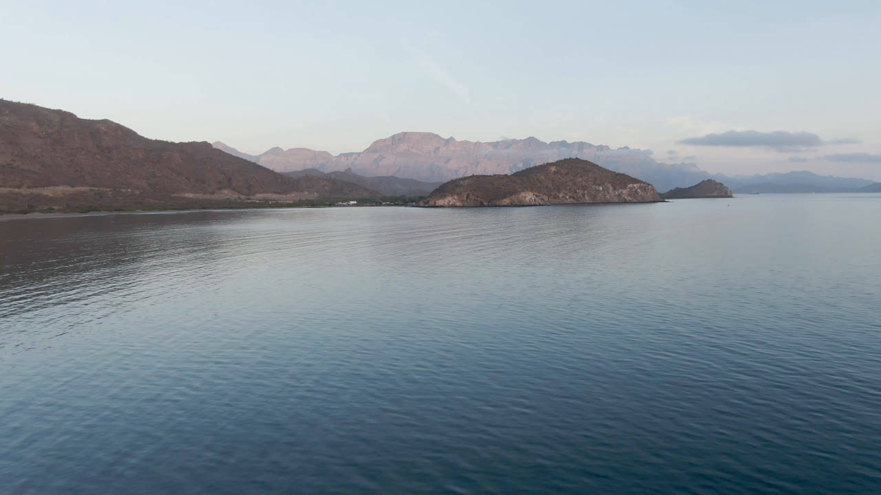 Opening frame of Danzante Bay in Loreto, Mexico, with calm blue water in front, low islands across the center, mountains beyond, and no visible people.
