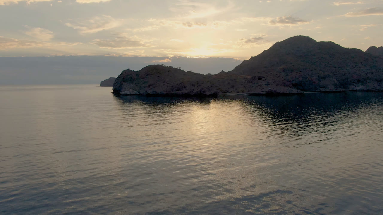 Danzante Bay Loreto water reflects a pale band of sunset below the rocky island and shadowed mountain ridge, with no visible people in the frame.