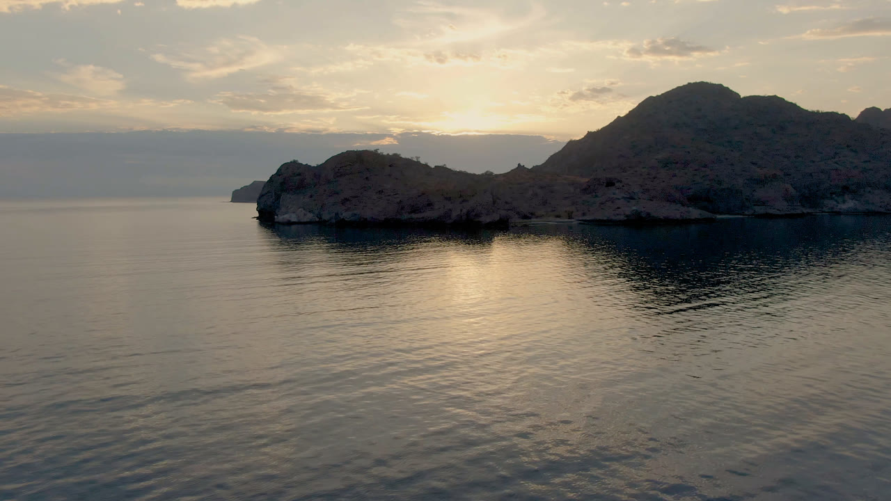 Rocky coastal island at right with open water and cloudy sky