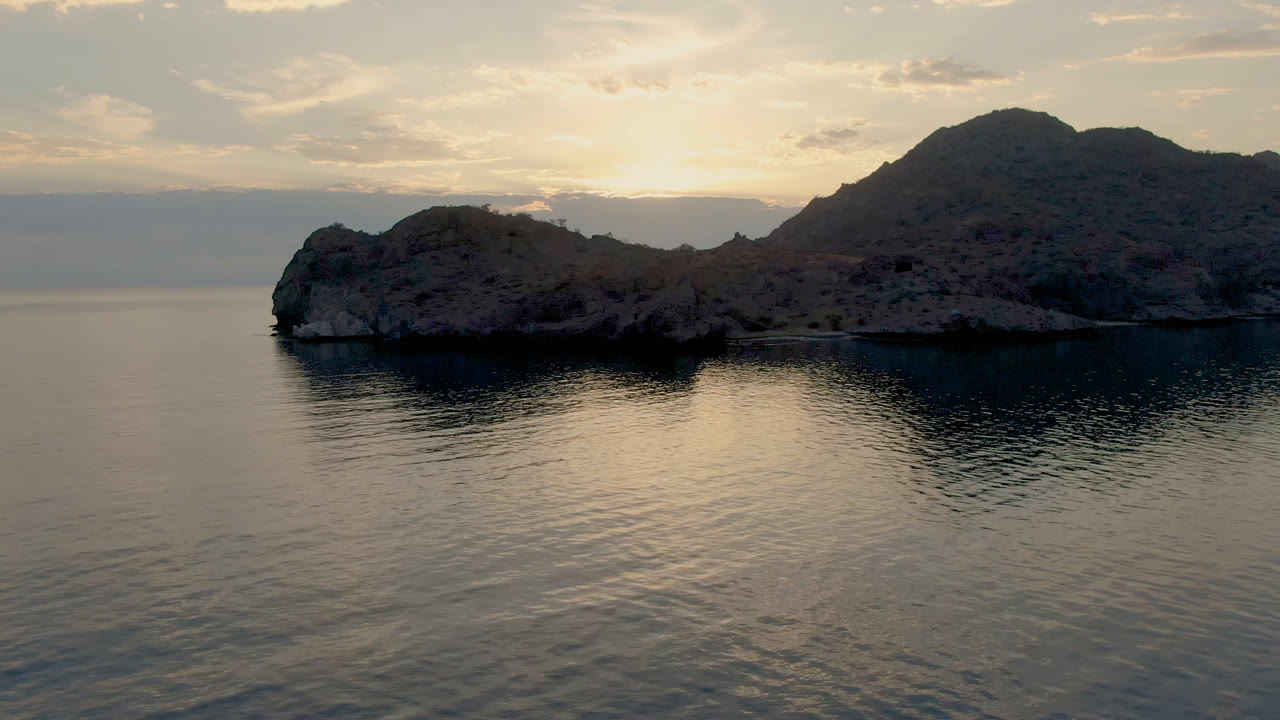 Mountain shoreline and rocky island reflected in rippled water.