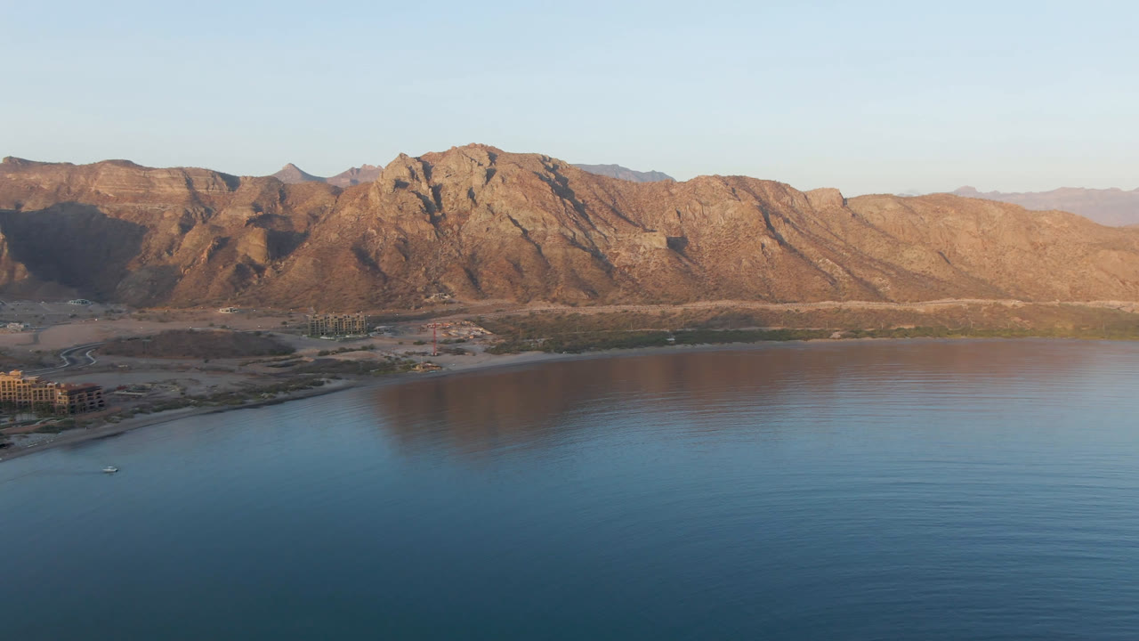 Calm bay water reflecting a rugged mountain ridge