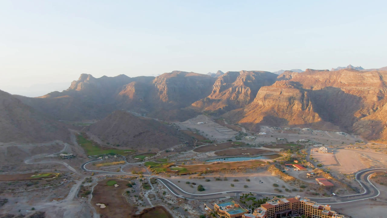 Aerial panorama of brown mountains, resort construction, roads, and small blue water areas