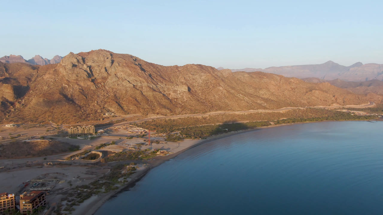 Danzante Bay coastline with blue water, desert road, buildings, and mountains.