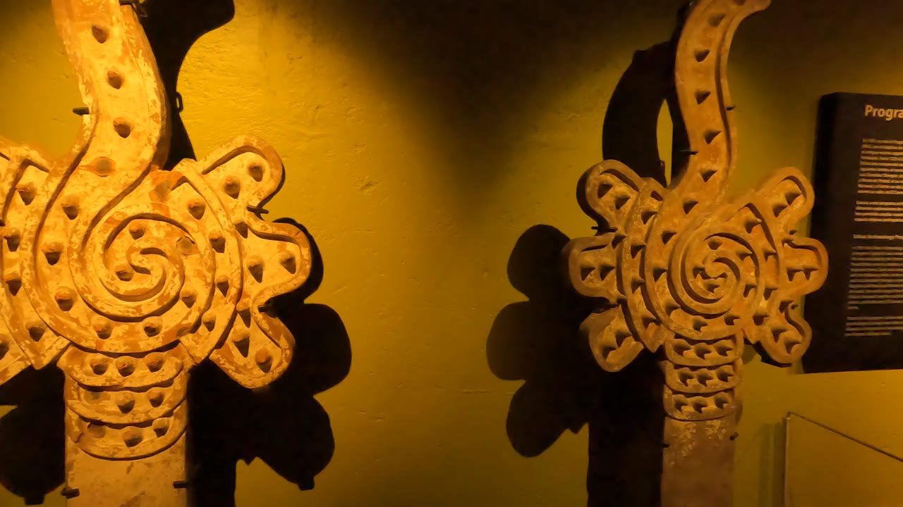 A decorative carved form dominates the right side while a museum information panel is partly visible behind it in Mexico City, with no visible people.