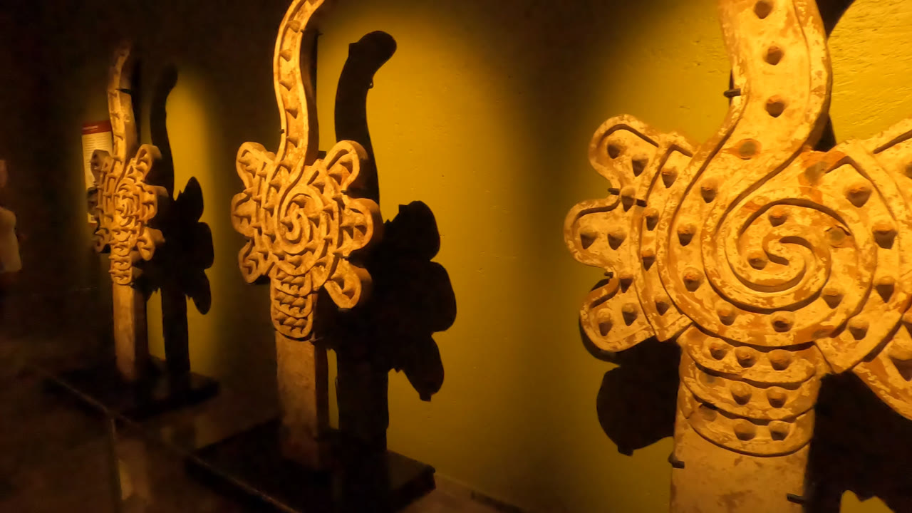 Wider museum view with two wooden carvings and a wall label.