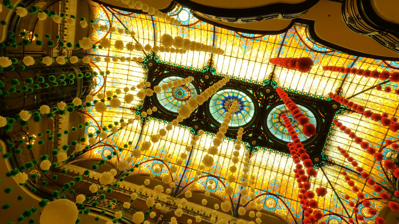 Backlit stained glass ceiling with hanging colored decorations.