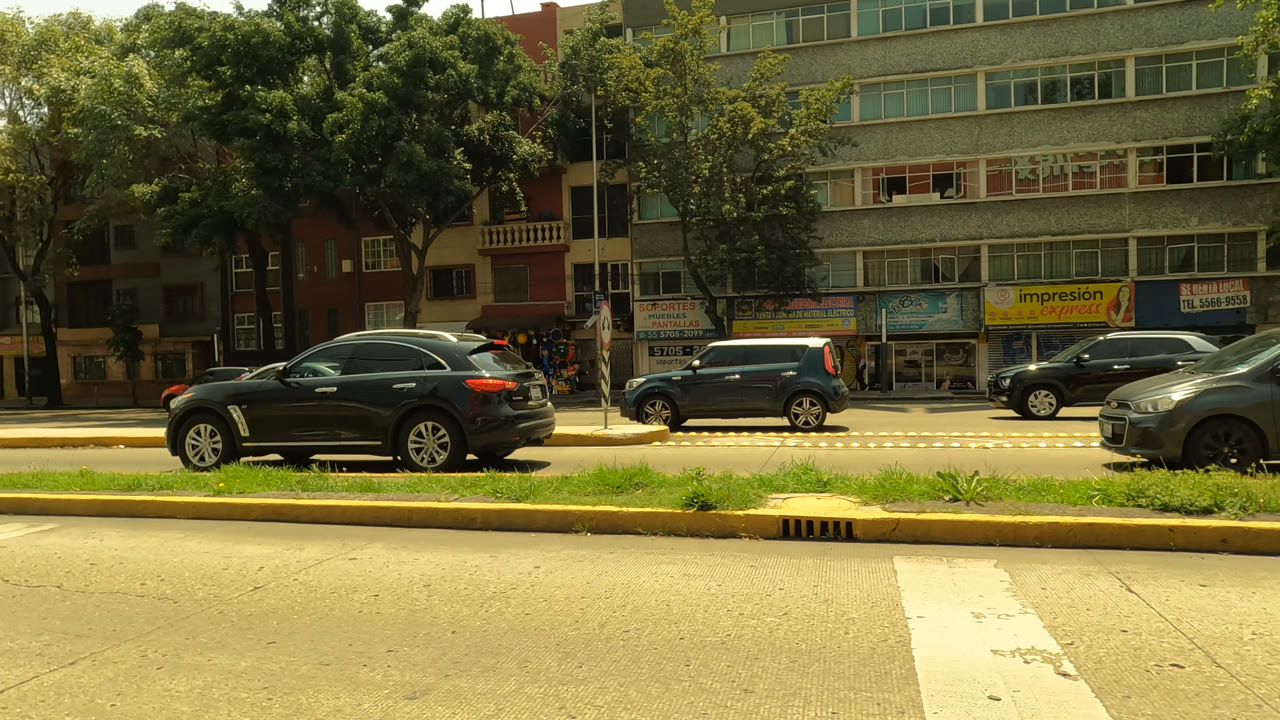 Black SUV and compact cars on a sunny urban street