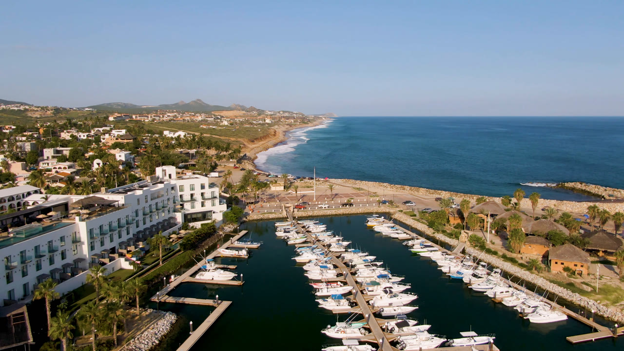 Aerial view of boats docked in a marina beside a beach and ocean.