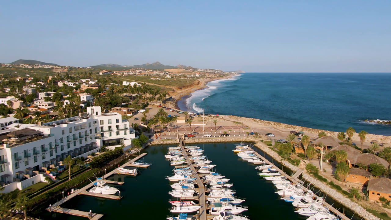 Aerial view of boats docked in a marina beside a beach and ocean.