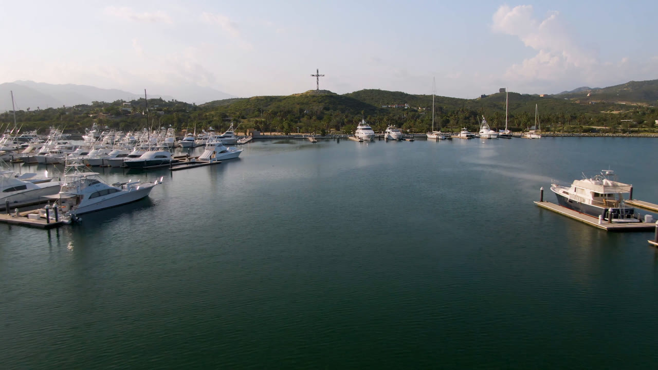 Marina docks and boats across calm water with mountains and clouds in the background.