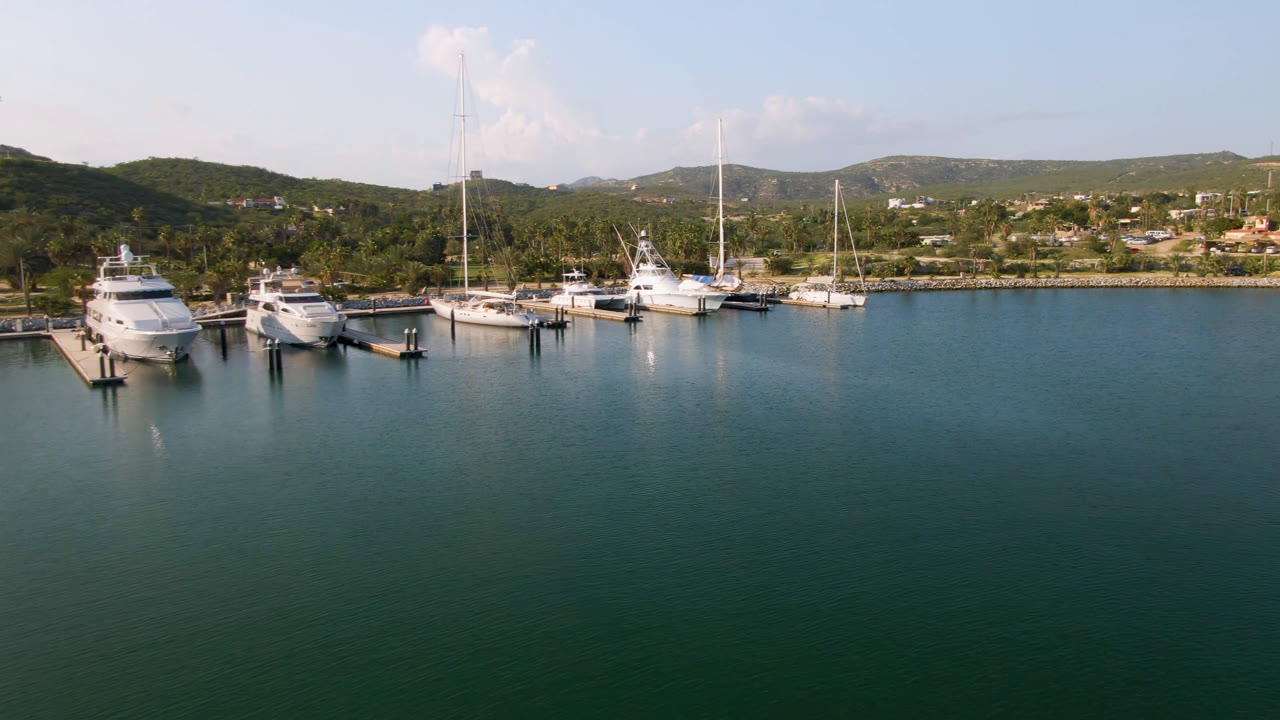 Aerial view of yachts and sailboats docked beside calm green-blue water