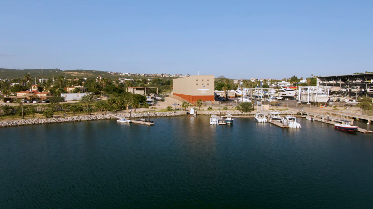 Wide aerial harbor view with docked boats and a waterfront building