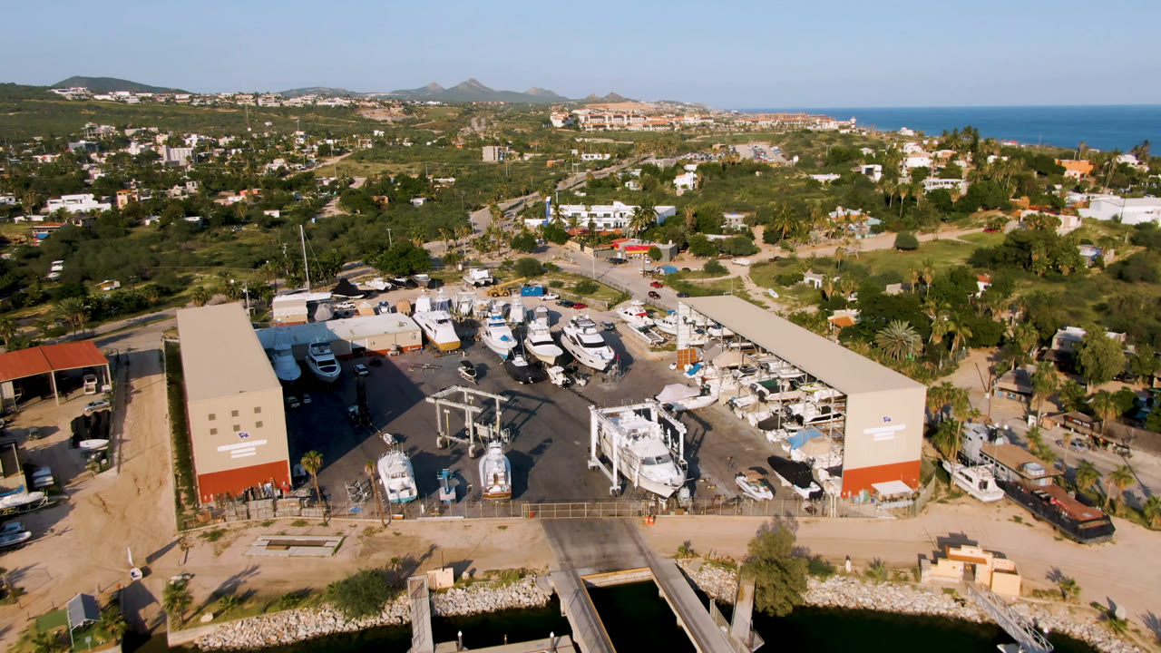 Aerial view of boats parked beside long marina sheds near the ocean